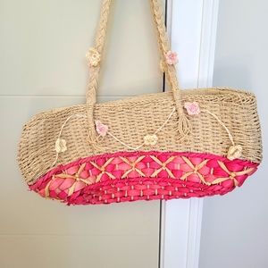 Woven grass bag with pink and white floral details.